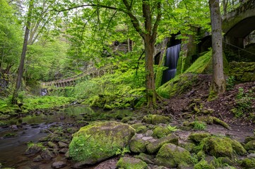 Sticker - Picturesque waterfall cascading down a rocky cliff face surrounded by lush greenery