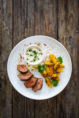 Wall Mural - Grilled pork loin steaks with fried potatoes on wooden table