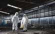 Workers wear protection suit checking chemical in old factory. Protecting Against Hazards and Contamination. Emergency Response to a Radioactive Accident.