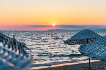 Wall Mural - The straw umbrella by the beach on an amazing sunset