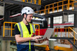© Supavadee - Caucasian man in uniform and helmet holding tablet looking at checklist checklist and doing electric train maintenance report in electric train depot