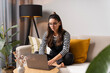 © Andrei - Charming focused multi-ethnic woman with glasses working on laptop from home in cozy room