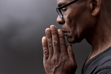 Wall Mural - black man praying to god with hands together Caribbean man praying stock photo	