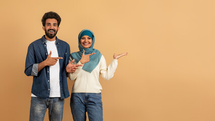 Poster - Check This. Cheerful Muslim Couple Pointing At Empty Palm