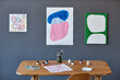 © Seventyfour - Workplace of artist, painter or designer with wooden desk with supplies standing by grey wall with masterpieces created by students of studio