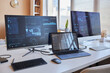 © Seventyfour - Row of three desktop computers with online graphic data on screens standing on workplace of IT engineer in office environment