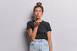 © WHstudio Leushin N - Lovely young Caucasian woman blowing air kiss at camera being flirty sending her love to someone keeps lips rounded palm towards camera dressed in casual black t shirt and jeans isolated on white