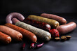 Assorted raw homemade sausages on black background