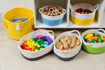 Wall Mural - Colorful storage baskets on shelves. White shelving with rainbow wooden toys in cloth stylish baskets. Organizing and storage ideas in nursery. Interior design.