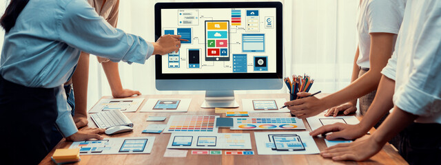 Panorama shot of front-end developer team brainstorming UI and UX designs for mobile app on laptop computer screen. User interface development team planning for user-friendly UI design. Scrutinize
