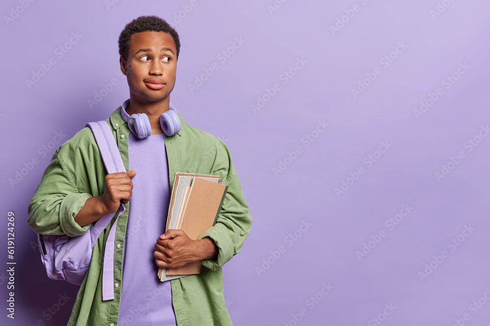 Horizontal shot of male student dressed in casual clothes carries ...