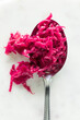 Bright pink beet and cabbage sauerkraut on a large spoon.