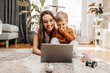 © Dusko - Happy middle age woman playing with her little son at home. They are using smart phone and laptop computer for playing, learning and online surfing.