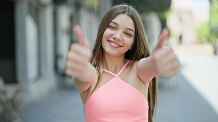 Sticker - Young beautiful girl smiling confident doing ok sign with thumbs up at street