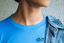 Teenage Boy With Autism Infinity Rainbow Symbol Sign Metallic Pin Brooch On T-shirt. World Autism Awareness Day, Autism Rights Movement, Neurodiversity, Autistic Acceptance Movement