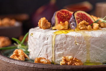 Wall Mural - Camembert cheese with fig fruits, honey, walnuts and rosemary on dark background. French appetizer. Close up
