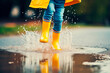 © Creative Clicks - Feet of child in yellow rubber boots jumping over puddle in rain