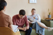 © Seventyfour - Rear view of psychologist making notes in document while talking to young couple