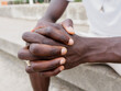 © ADDICTIVE STOCK - Crop anonymous black man with crossed fingers sitting on bench