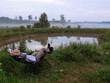 © mark_gusev - Man in blue shirt looking at beautiful nature at dusk laying down on a armchair. Private high value property with lake. Relaxing after work and enjoy calm nature scenery with fog.