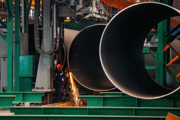 Wall Mural - Worker cleans welded seam on steel pipe using grinding machine