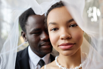 Wall Mural - Closeup portrait of black couple as bride and groom looking at camera under veil