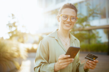 female worker in green blouse and eyeglasses using smartphone