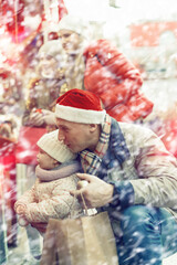 Happy father with little daughter in his arms choosing Christmas decoration at Christmas fair