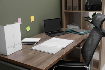 Wall Mural - Folder with punched pockets and laptop on wooden table in office