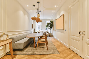 a living room with wood flooring and white walls, including a wooden table and two chairs in front of the couch