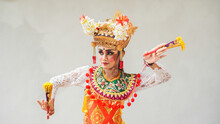 Girl Wearing Balinese Traditional Dress With A Dancing Gesture On White Background With Hand-held Fan, Crown, Jewelry, And Gold Ornament Accessories. Isolated Balinese Dancer Woman Portrait
