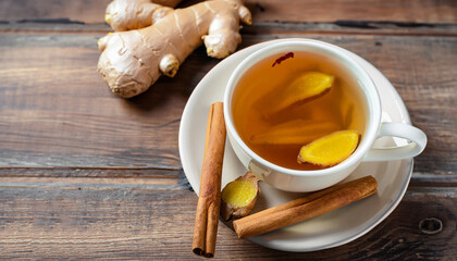 Wall Mural - Cup of tea with ginger and cinnamon on wooden background