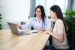 © tong2530 - Asian female doctor consulting patient or client while looking at treatment guidelines on laptop with medical technology at the clinic. Health care concept. selective focus on patient.