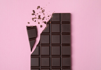 Canvas Print - Broken dark chocolate bar on pink background, flat lay