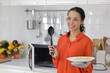 © feeling lucky - Happy latin woman smelling and showing food after finished cooking. Young female preparing delicious meal and learning from internet with computer in kitchen. Healthy and lifestyle concept