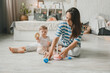 © inna717 - Beautiful young mother plays and teaches her baby 6 months old on the floor in the living room.mom and baby play with toys