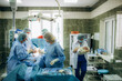 surgeons perfoming surgery operation of abdominal cesarean section during child delivery birth at clinic operating room.
