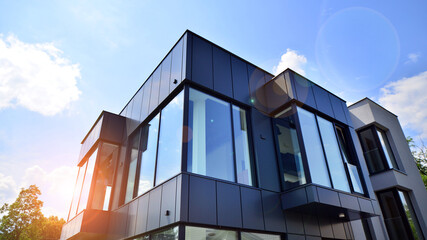 Graphite facade and large windows on a fragment of an office building against a blue sky. Modern aluminum cladding facade with windows.