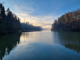 Sticker - Scenic landscape with a tranquil lake surrounded by lush woodland in a peaceful morning light