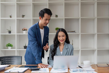 Wall Mural - Business man having a discussion with his colleague in an office. Two business people using a laptop in a meeting. Teamwork and collaboration between business professionals