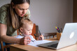 © FOTO_STOCKER - happy family mother and little baby daughter do homework using laptop with mother help, online learning education class,