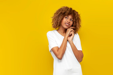 Wall Mural - young curly american girl with braces shy and dreaming over yellow isolated background