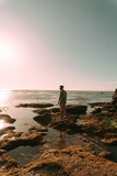 Fototapeta Na ścianę - Podróżnik o zachodzie słońca na tle oceanu stojący przy skałach.