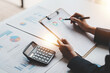 © Suphakant - Accountant working on desk using calculator to calculate financial report in office business accounting finance concept