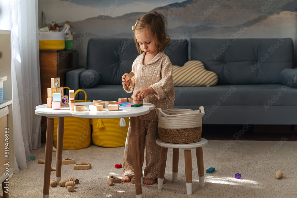 A little girl playing with colorful wooden blocks on the table in ...