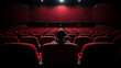© Keitma - One lonely person in a theater on red seat watching in front , back view
