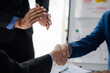 © pornpirose suparit - Business investor group holding hands, Two businessmen are agreeing on business together and shaking hands after a successful negotiation. Handshaking is a Western greeting or congratulation.