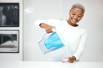 Wall Mural - Water, filter and black woman with jug in kitchen to refresh with glass, liquid and cold hydration. Happy, thirsty and female person pouring pure aqua beverage from pitcher for clean drinking at home