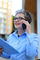 Sticker - Woman businessman talking on a smartphone, holding documents in her hands.