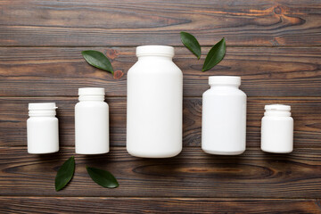 supplement pills with medicine bottle health care and medical top view. Vitamin tablets. Top view mockup bottle for pills and vitamins with green leaves, natural organic bio supplement, copy space